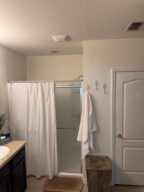 bathroom with vanity, a shower, tile patterned floors, and a textured ceiling