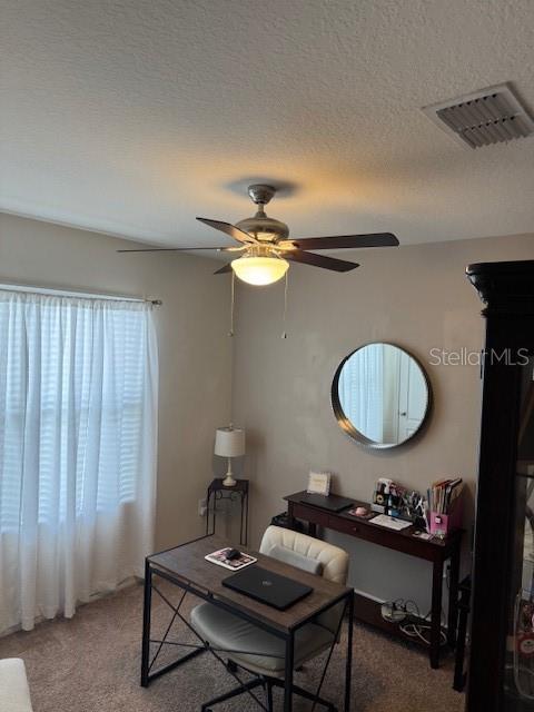 carpeted office space with ceiling fan and a textured ceiling