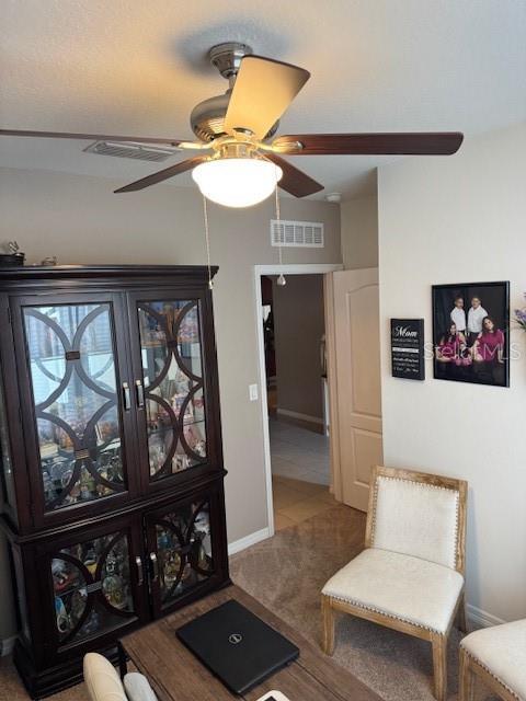 sitting room featuring ceiling fan and carpet