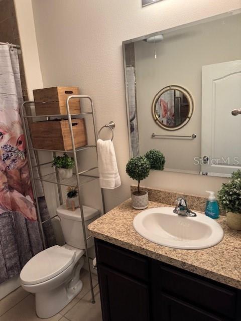 bathroom featuring tile patterned flooring, vanity, a shower with curtain, and toilet