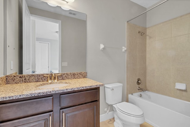 full bathroom featuring vanity, tiled shower / bath combo, and toilet