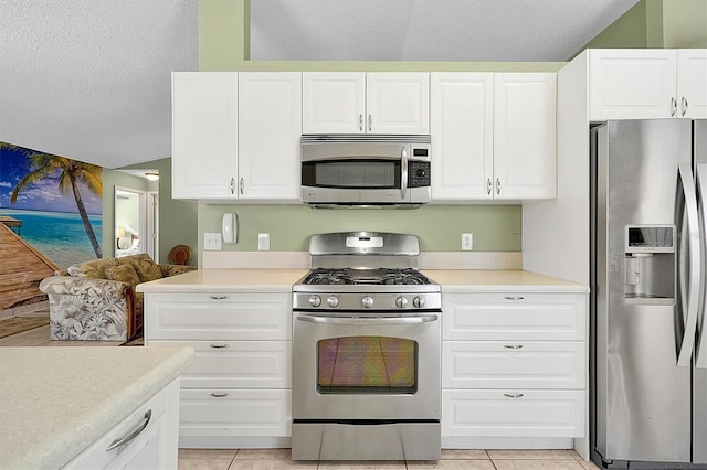 kitchen with light tile patterned flooring, white cabinets, a textured ceiling, and appliances with stainless steel finishes