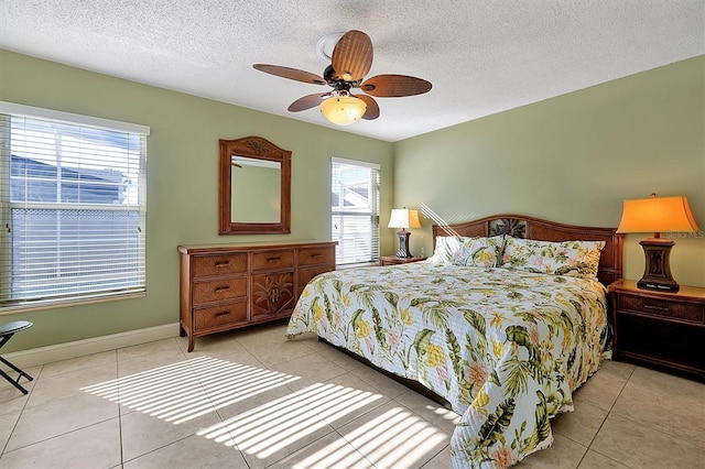 tiled bedroom featuring ceiling fan, a textured ceiling, and multiple windows