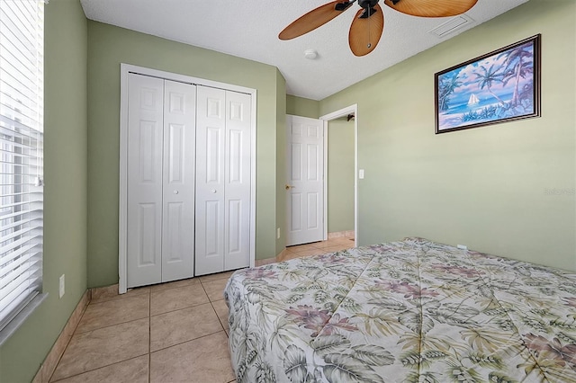 tiled bedroom featuring ceiling fan, a textured ceiling, and a closet