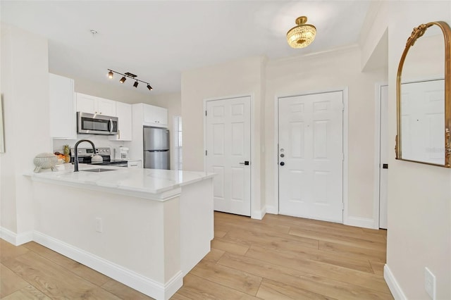 kitchen with light hardwood / wood-style floors, white cabinetry, kitchen peninsula, and stainless steel appliances