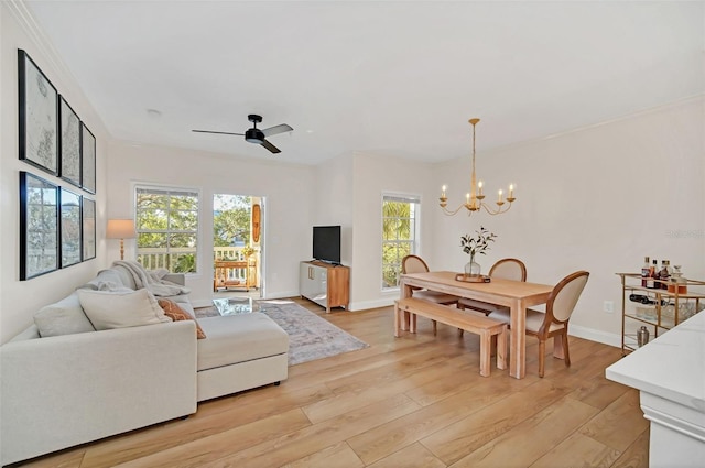 living room featuring crown molding, plenty of natural light, light hardwood / wood-style floors, and ceiling fan with notable chandelier