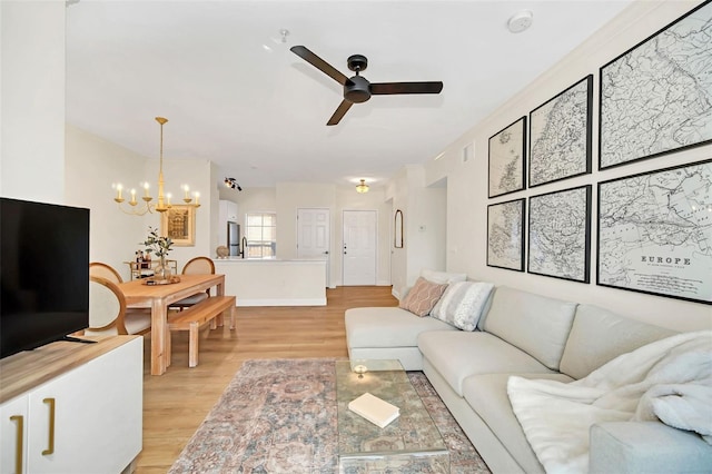 living room with ceiling fan with notable chandelier and light wood-type flooring