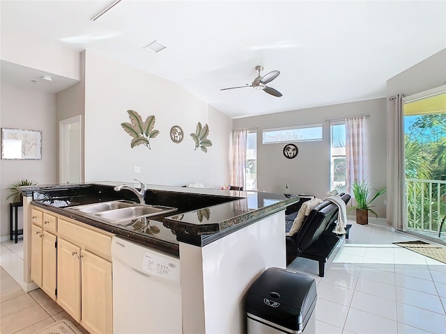 kitchen featuring dishwasher, lofted ceiling, sink, light tile patterned floors, and an island with sink