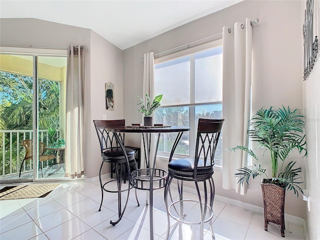 tiled dining room featuring plenty of natural light and lofted ceiling