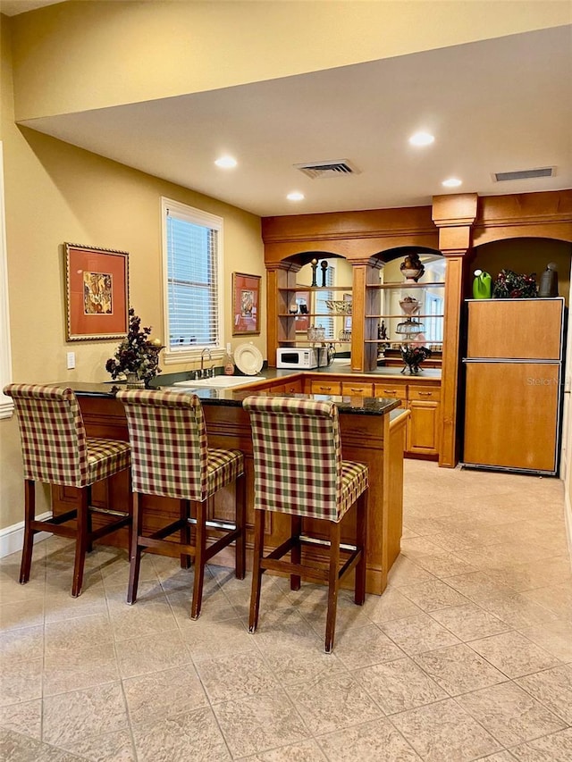 bar featuring refrigerator and sink