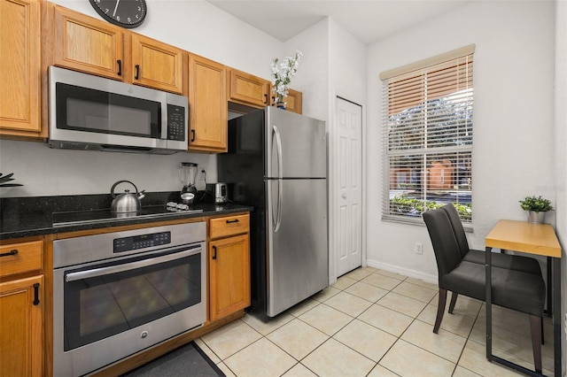 kitchen with plenty of natural light, stainless steel appliances, dark stone counters, and light tile patterned flooring