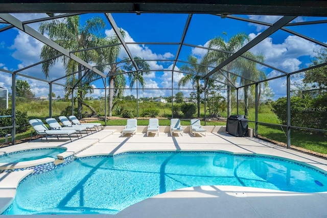 view of pool with a patio area, an in ground hot tub, and glass enclosure