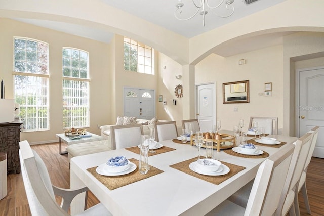 dining area featuring hardwood / wood-style floors, a healthy amount of sunlight, and a chandelier