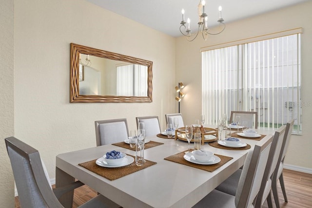 dining area with light hardwood / wood-style flooring and a notable chandelier