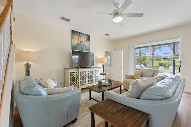 living room featuring ceiling fan, a textured ceiling, and light hardwood / wood-style flooring