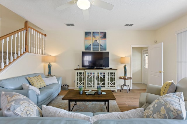 living room with hardwood / wood-style floors, a textured ceiling, and ceiling fan