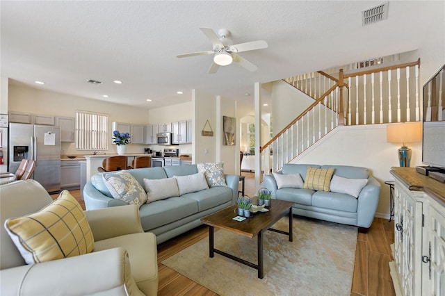 living room featuring ceiling fan, light hardwood / wood-style floors, and a textured ceiling