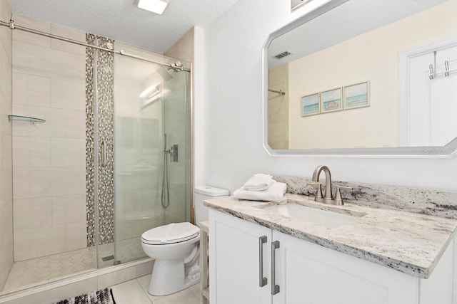 bathroom with tile patterned floors, walk in shower, vanity, a textured ceiling, and toilet