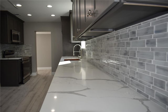 kitchen featuring backsplash, black / electric stove, light stone countertops, and sink