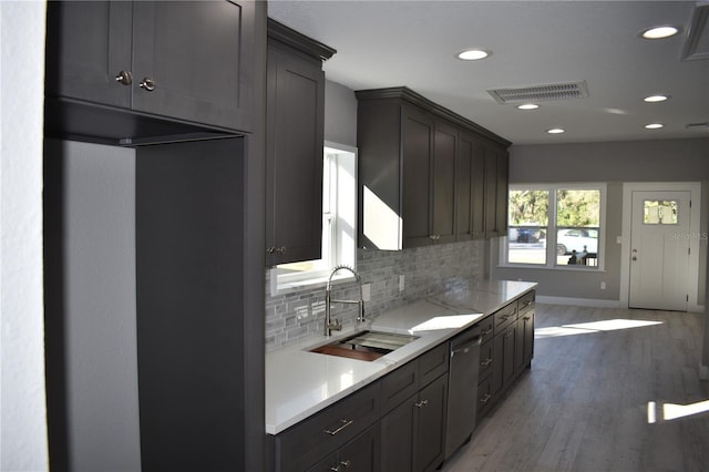 kitchen with backsplash, dark hardwood / wood-style floors, stainless steel dishwasher, and sink