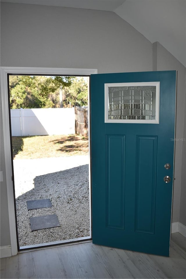 doorway with light hardwood / wood-style flooring and vaulted ceiling