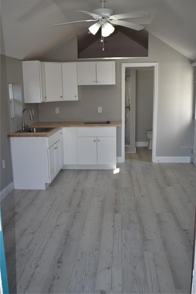 kitchen with vaulted ceiling, white cabinetry, ceiling fan, and sink