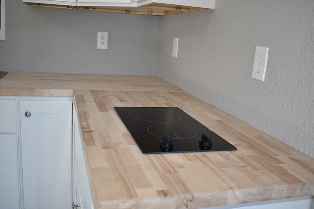 kitchen with black electric stovetop and white cabinetry