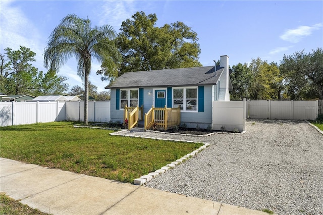 view of front of property featuring a front yard, a gate, a fenced backyard, and a chimney