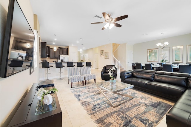 tiled living room with ceiling fan with notable chandelier