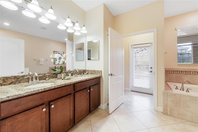 bathroom featuring tile patterned floors, a relaxing tiled tub, and vanity