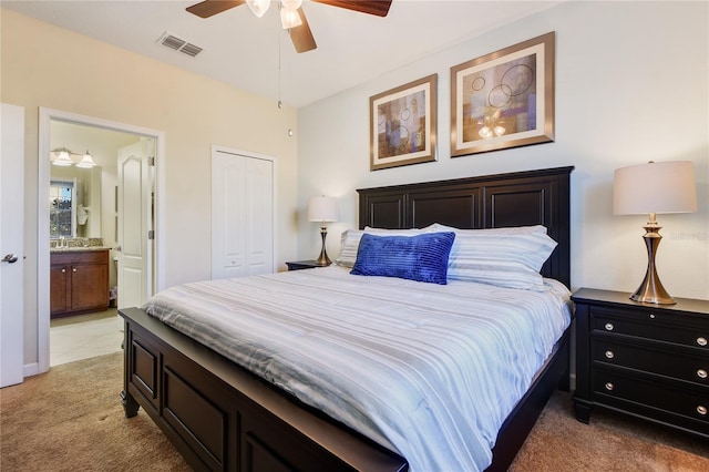 bedroom featuring ceiling fan, a closet, ensuite bathroom, and light carpet