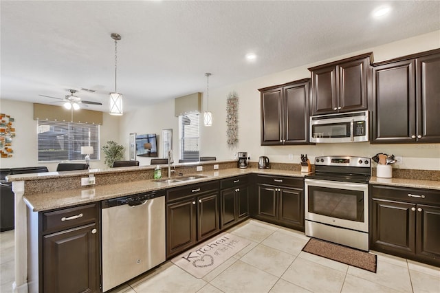 kitchen with kitchen peninsula, dark brown cabinets, stainless steel appliances, sink, and hanging light fixtures