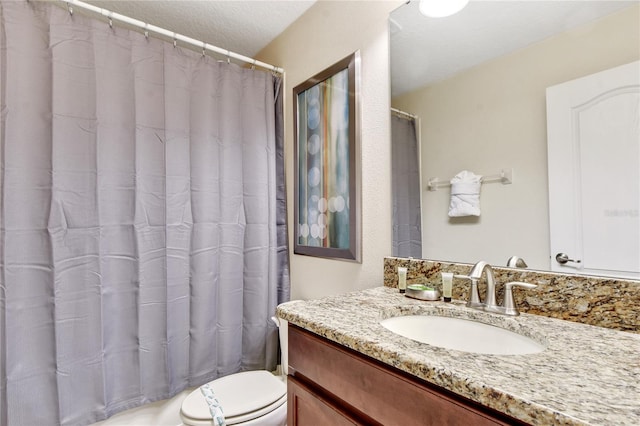 bathroom with vanity, toilet, and a textured ceiling