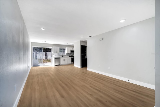 unfurnished living room with light hardwood / wood-style flooring and sink