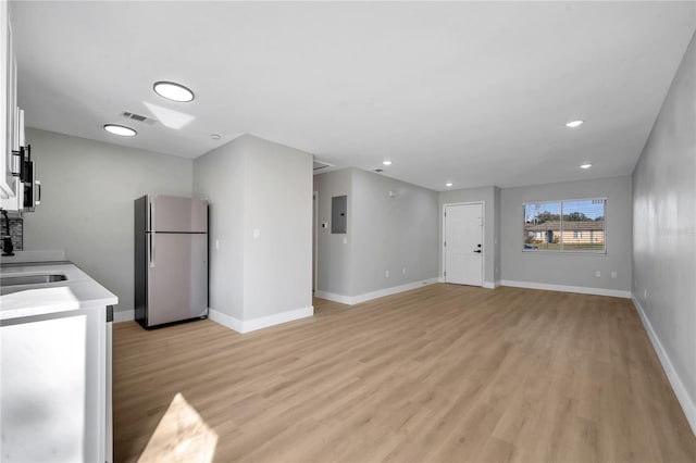 unfurnished living room with sink, light wood-type flooring, and electric panel