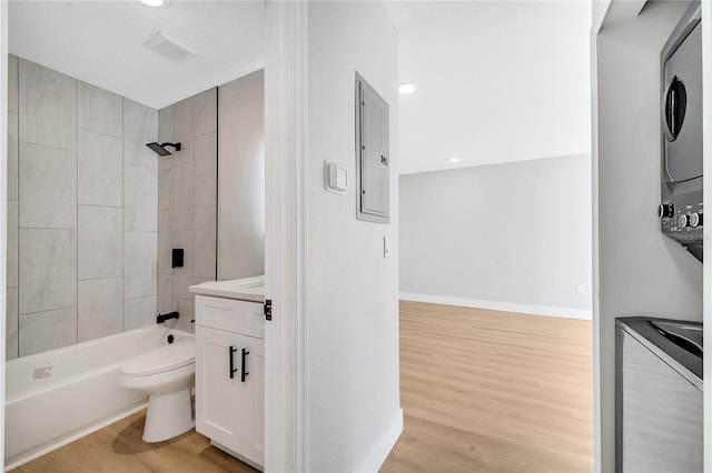 full bathroom with tiled shower / bath combo, toilet, vanity, electric panel, and hardwood / wood-style flooring