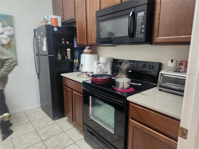 kitchen with black appliances and light tile patterned flooring