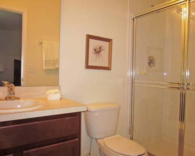 bathroom with an enclosed shower, vanity, and toilet