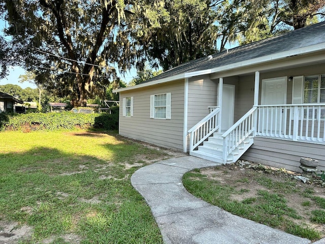 doorway to property with a porch and a yard