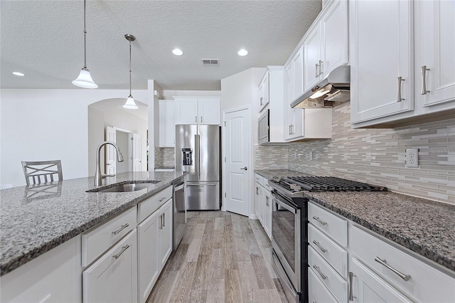 kitchen featuring decorative light fixtures, sink, stainless steel appliances, white cabinets, and light stone counters