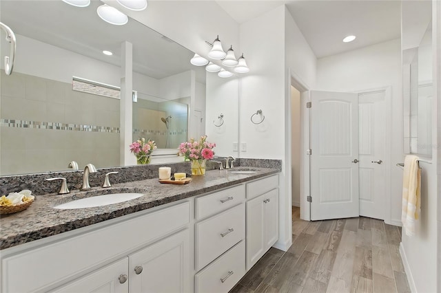 bathroom featuring hardwood / wood-style flooring, vanity, and a tile shower