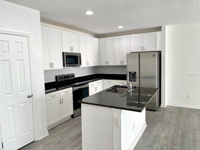 kitchen featuring white cabinetry, stainless steel appliances, and a kitchen island with sink