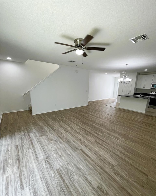 unfurnished living room with a textured ceiling, ceiling fan with notable chandelier, light hardwood / wood-style flooring, and sink