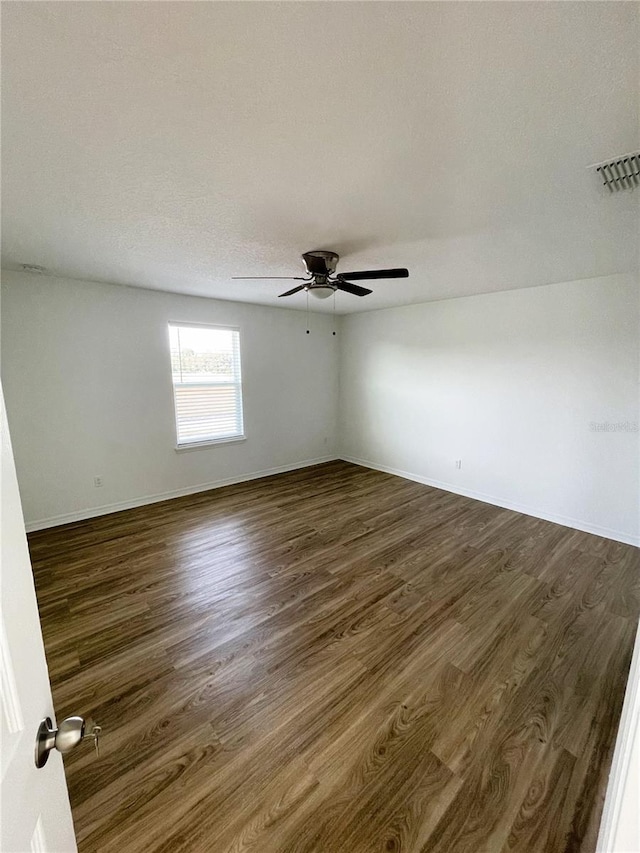 empty room featuring a textured ceiling, ceiling fan, and dark wood-type flooring