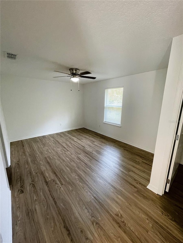 empty room featuring ceiling fan, dark hardwood / wood-style flooring, and a textured ceiling