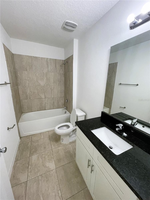 full bathroom with tiled shower / bath combo, tile patterned flooring, a textured ceiling, toilet, and vanity