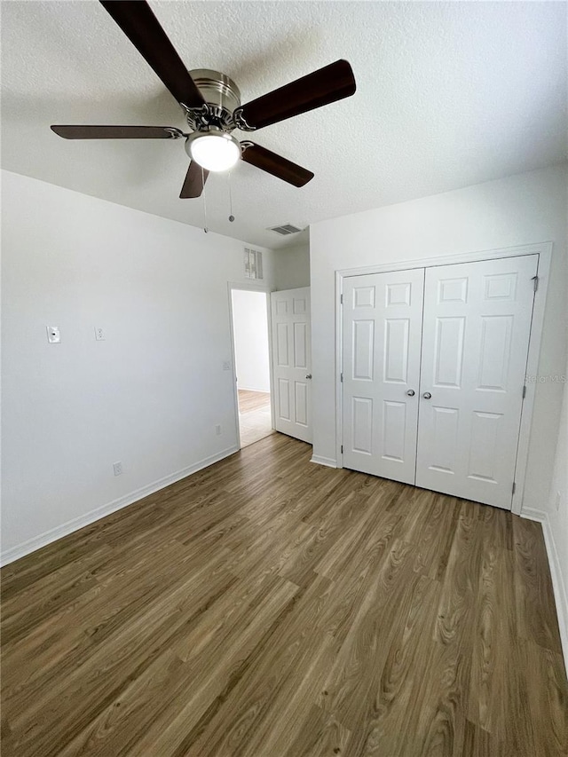 unfurnished bedroom featuring a closet, ceiling fan, hardwood / wood-style floors, and a textured ceiling