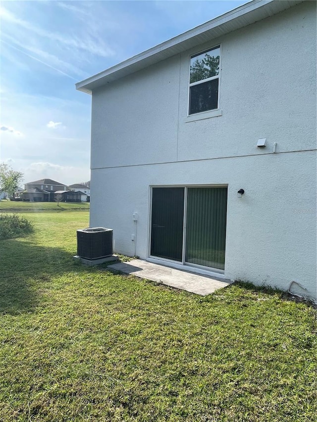 back of house featuring a yard and central AC