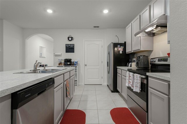 kitchen featuring light tile patterned flooring, appliances with stainless steel finishes, gray cabinets, and sink