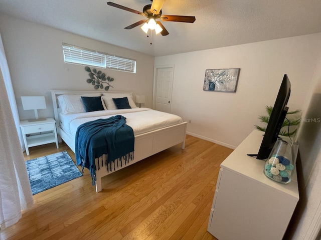 bedroom with a textured ceiling, light wood-type flooring, and ceiling fan